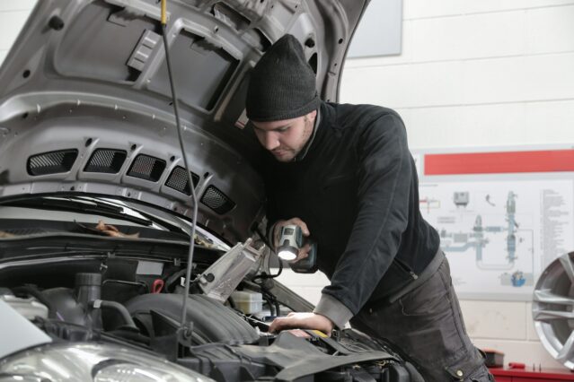 mechanic inspecting under car bonnet